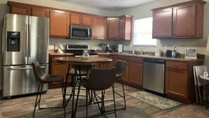 Una cocina moderna con electrodomésticos de acero inoxidable, armarios de madera y un comedor con sillas.