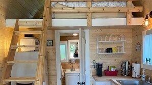 Un intérieur en bois comprenant une cuisine, un escalier et une porte donnant sur une autre pièce.