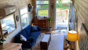 L’intérieur chaleureux d’un chalet avec un canapé bleu, un plancher en bois, une table à manger et un coin cuisine.
