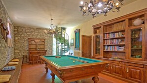 A billiards room with a pool table, wooden cabinets, and a bookshelf. - Zeffiro – Holiday country villa with  pool and tennis court near Cortona, Tuscany (Pergo)