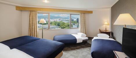 Habitación de hotel con dos camas, televisión y vista a la ciudad.
