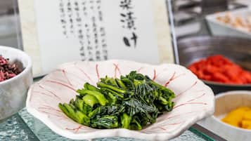 A bowl of cooked greens on a table with a menu in the background.