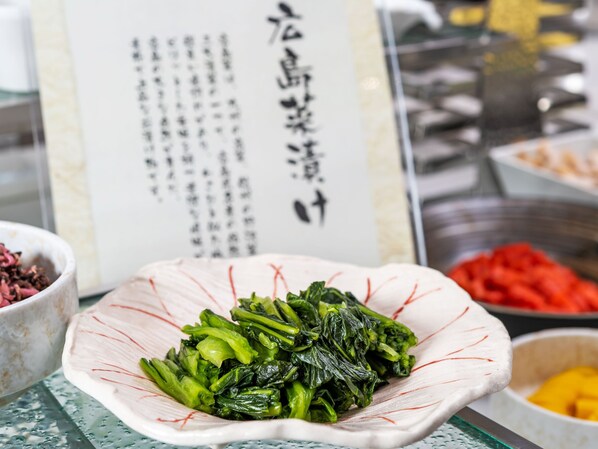 Un bol de légumes verts cuits est posé sur une table, avec un menu en arrière-plan.