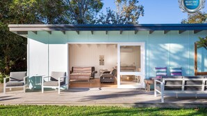 A modern, light blue house with a spacious patio area, a dining table, and comfortable seating. - Beachwood - Firepit - Pet Friendly - 2 Mins Walk to the Beach (Callala Beach)