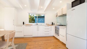 Una cocina moderna con armarios blancos, horno empotrado, microondas y refrigerador.