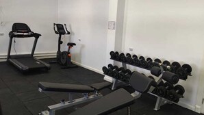 A gym with a treadmill, elliptical, bench press, and a rack of dumbbells. - Sulo Aksay Hotel (Aksay)