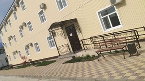 A multi-story building with a beige facade, a black gate, and a checkered pavement. - Sulo Aksay Hotel (Aksay)