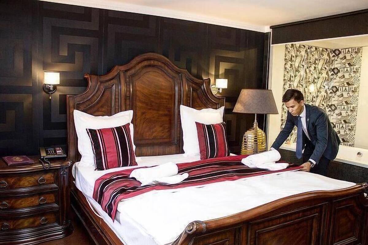 A neatly made bed with a wooden headboard, two bedside lamps, and a nightstand with a telephone.