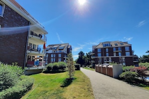 A residential building with a balcony, a paved walkway, and a well-maintained lawn. - High Lith Apartment 3-05 (Cuxhaven)