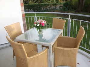 A glass-top table with wicker chairs on a balcony. - High Lith Apartment 3-05 (Cuxhaven)