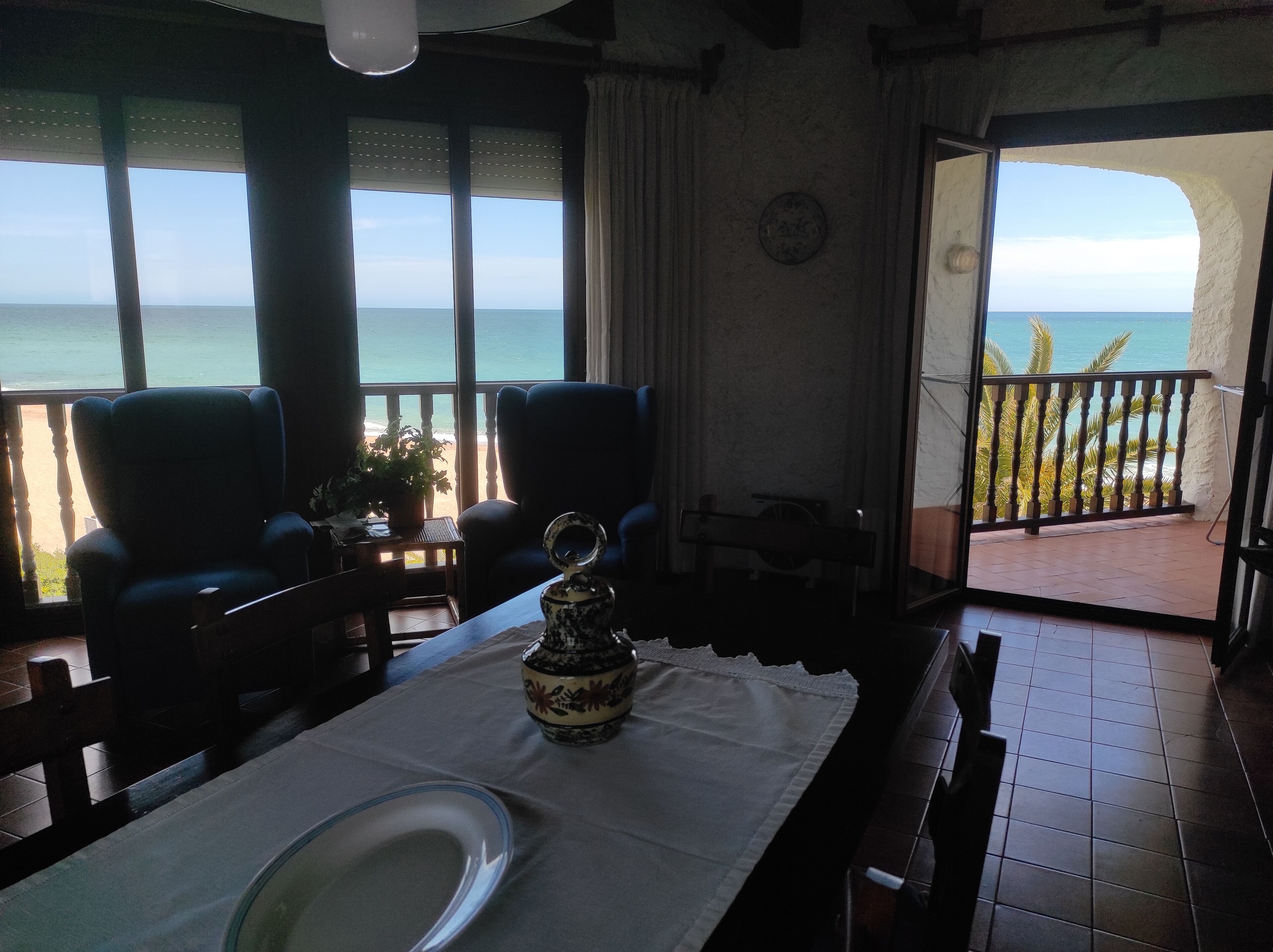 Un comedor con una mesa preparada para dos, con vista a un balcón y al mar.