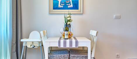 A dining area with a table, chairs, and a painting on the wall.