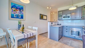 Una cocina moderna con armarios grises, horno empotrado y zona de comedor con mesa y sillas.