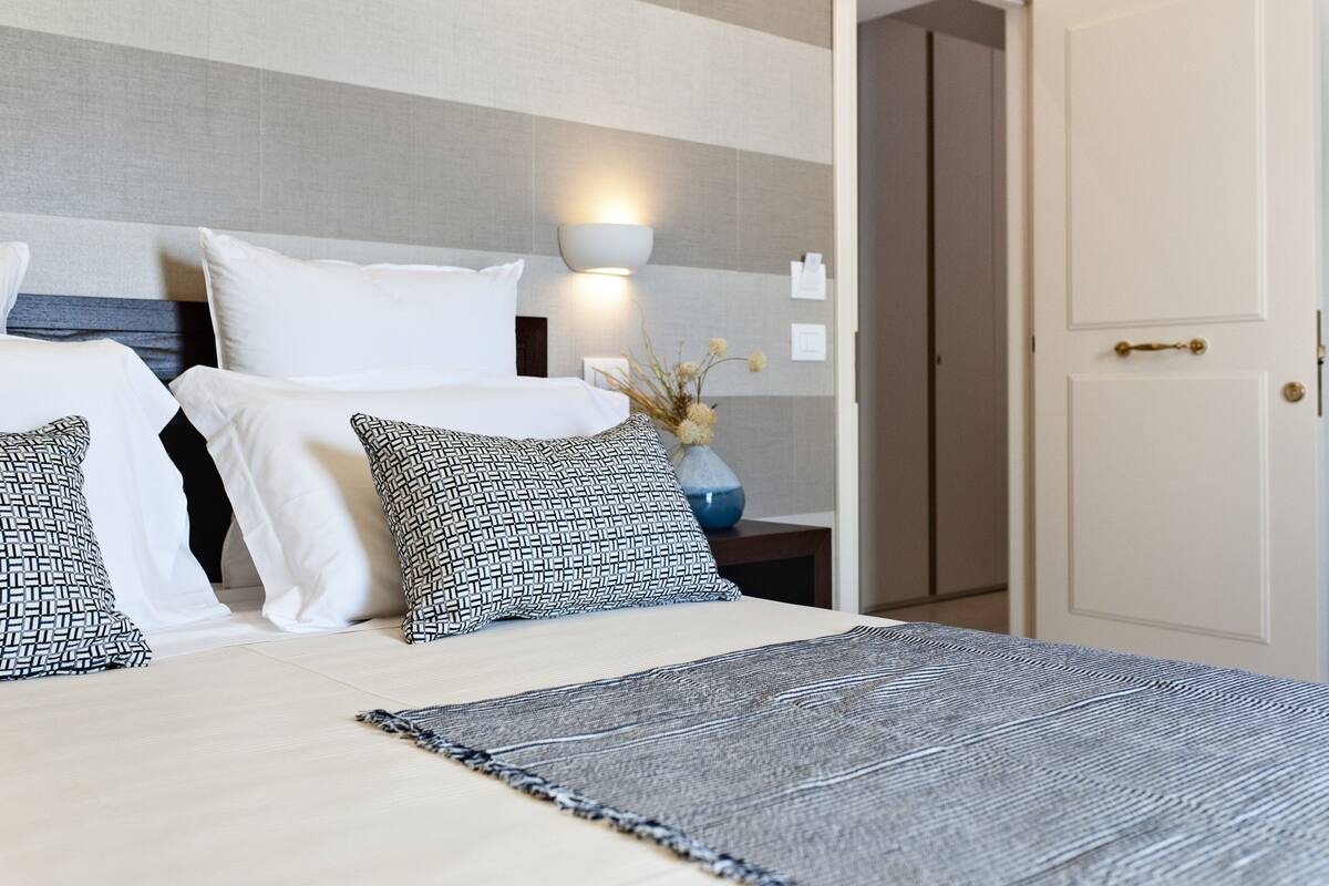 Ein Hotelzimmer mit einem Bett, einem Nachttisch, einer Lampe und einer Tür.