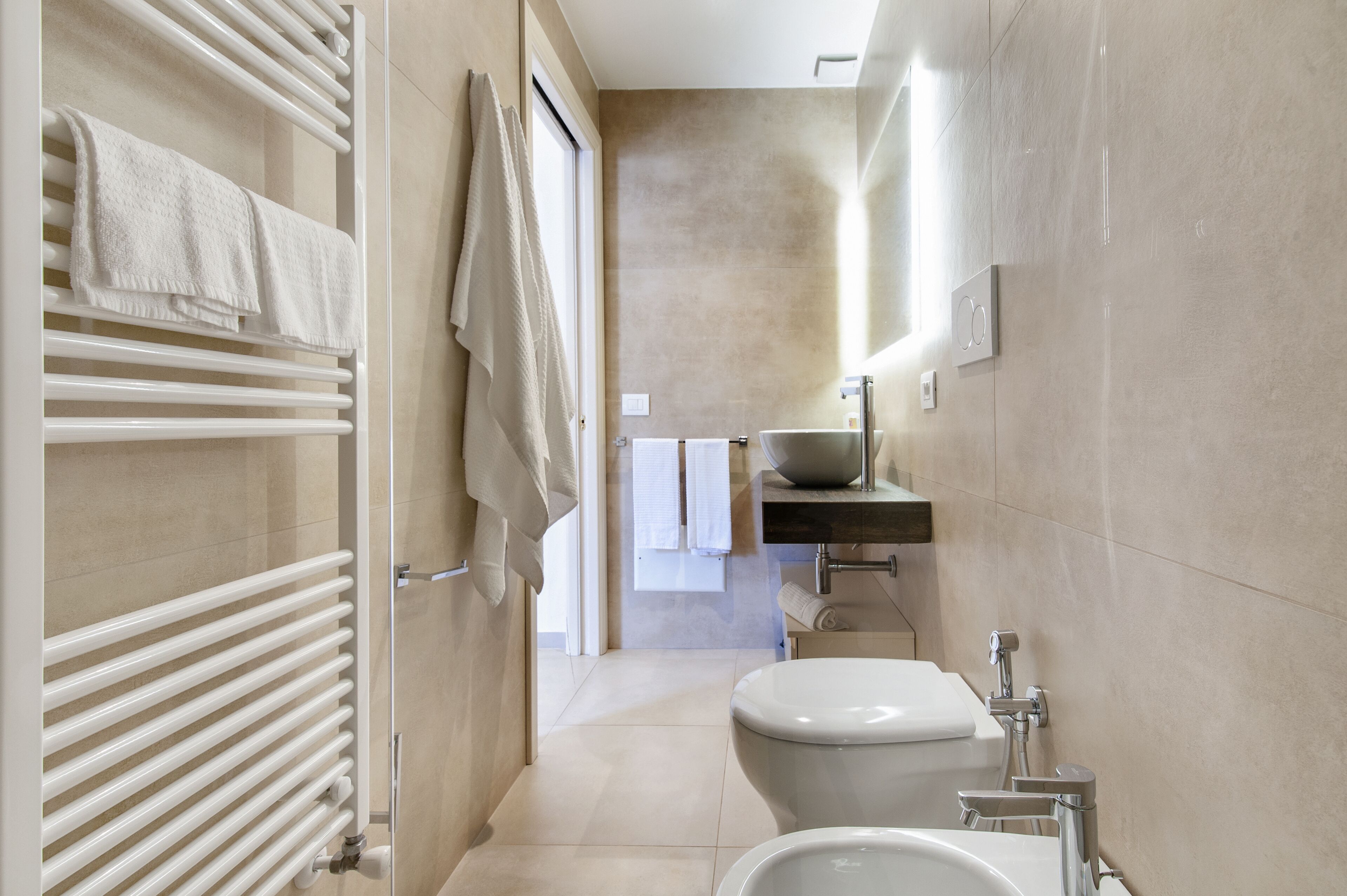 Un bagno moderno con una vasca da bagno bianca, un lavandino con specchio e un water.