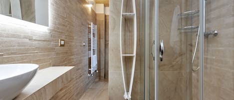 A modern bathroom with a glass-enclosed shower, a white sink, and a tiled floor.