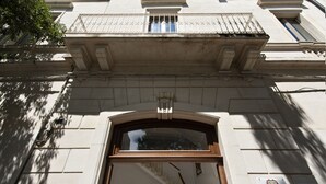 Una entrada de edificio con un amplio arco, una escalera que conduce al interior y una placa en la pared.