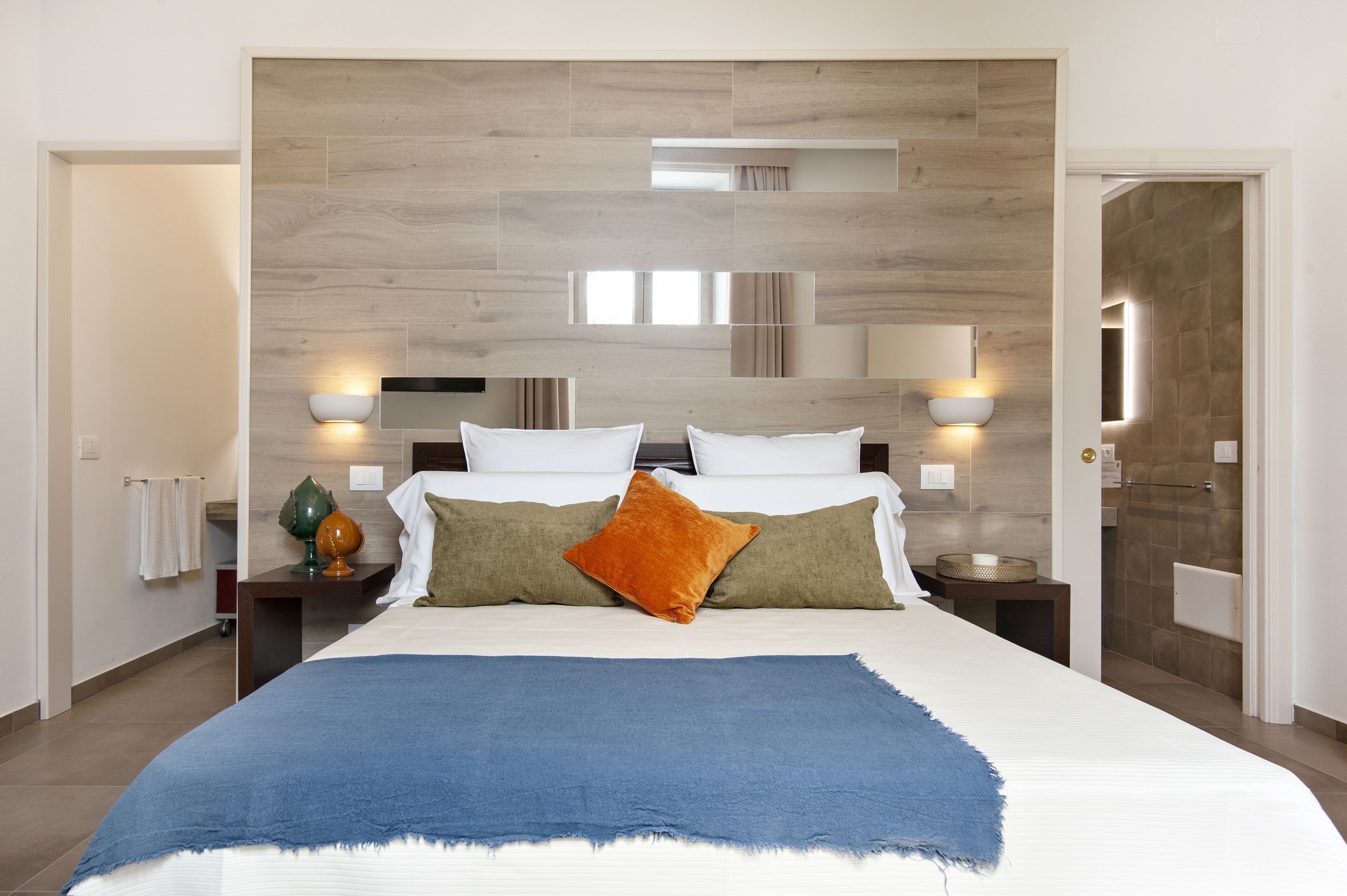 A modern bedroom with a large bed, two bedside tables, and a wooden headboard.