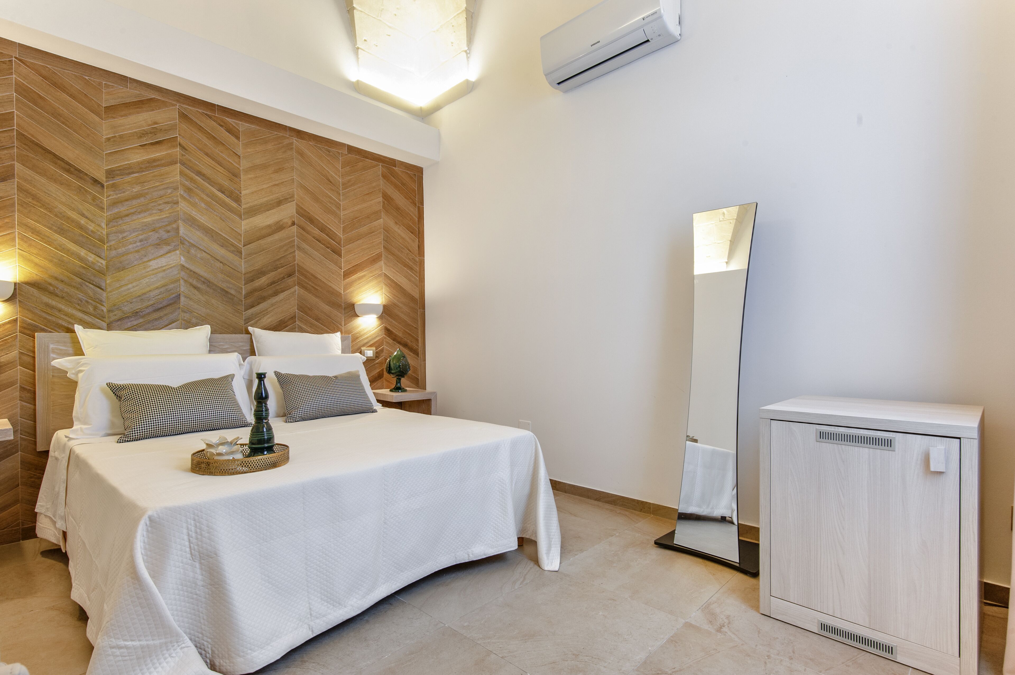 Une chambre d’hôtel comprenant un lit, des tables de chevet, un miroir et une armoire.