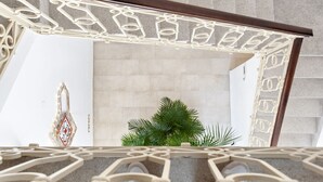 Una escalera con un diseño geométrico en la barandilla, un adorno de pared y una planta verde.