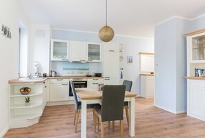 Et moderne køkken med hvide skabe, et træspisebord og en hængende lampe.