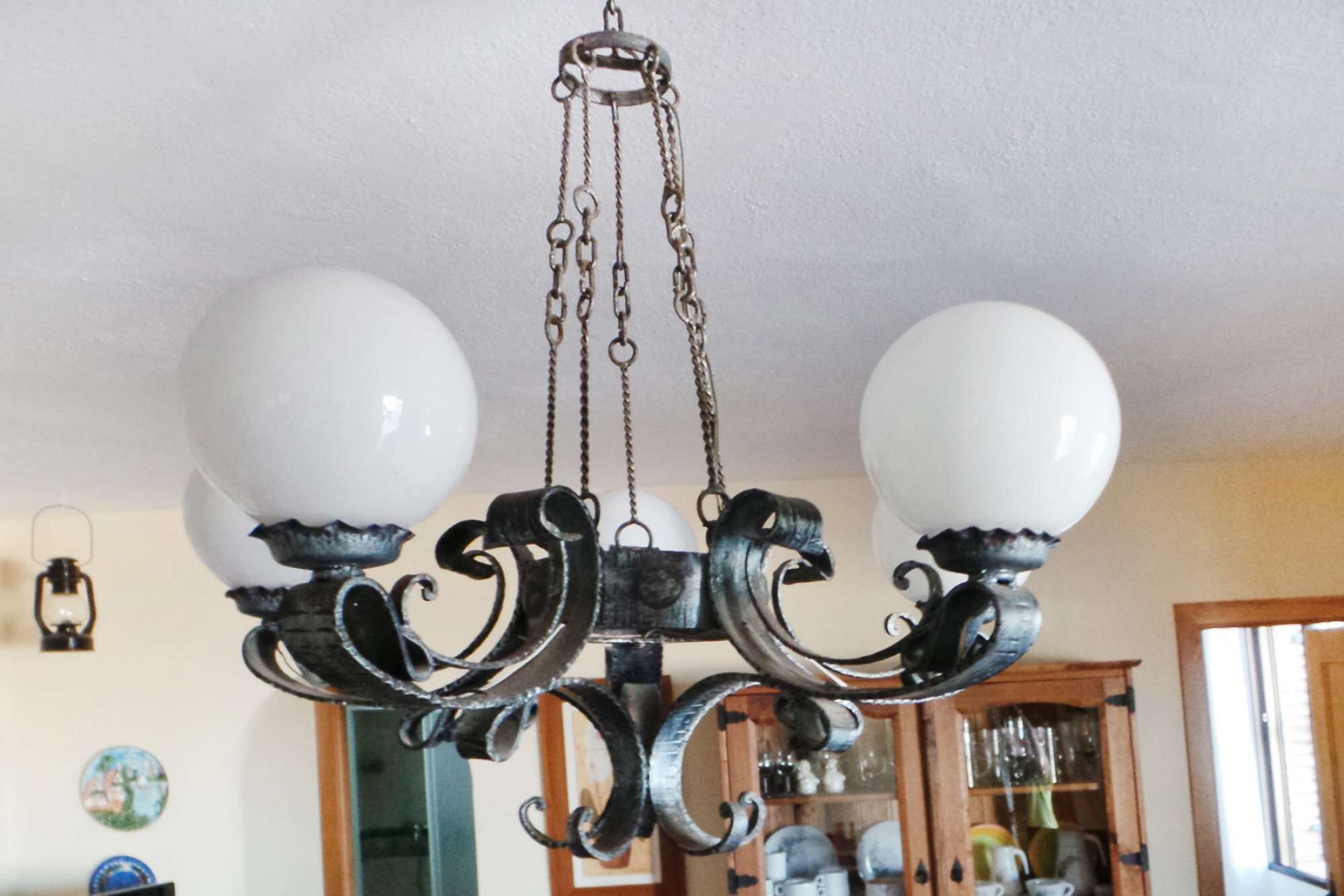 Un candelabro con dos esferas blancas y detalles metálicos ornamentales negros.
