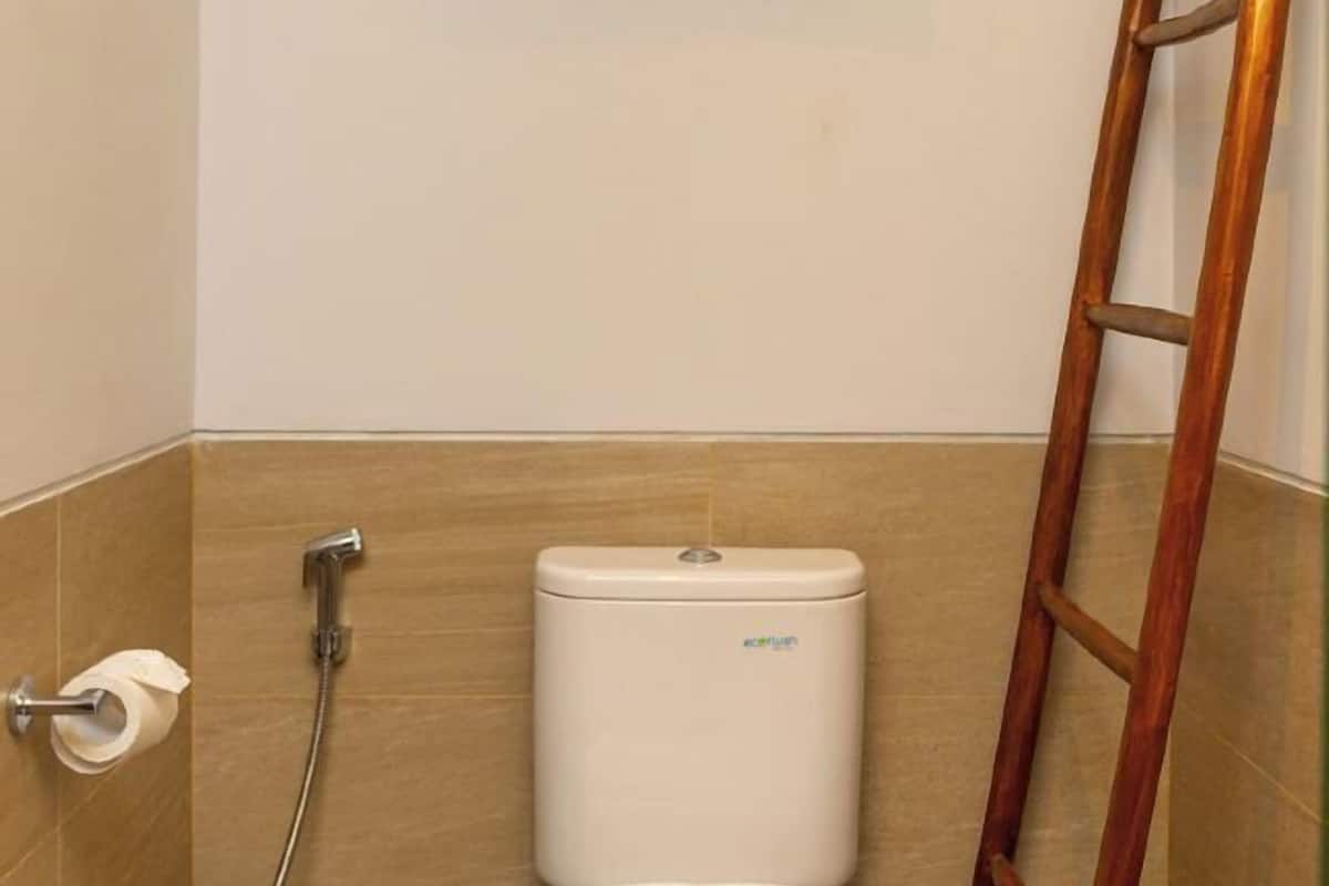 Ein Badezimmer mit Toilette, Dusche und einer Holzleiter.