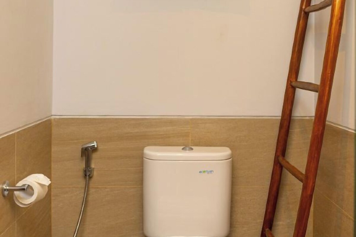 Un bagno con un water, una doccia e una scala in legno.