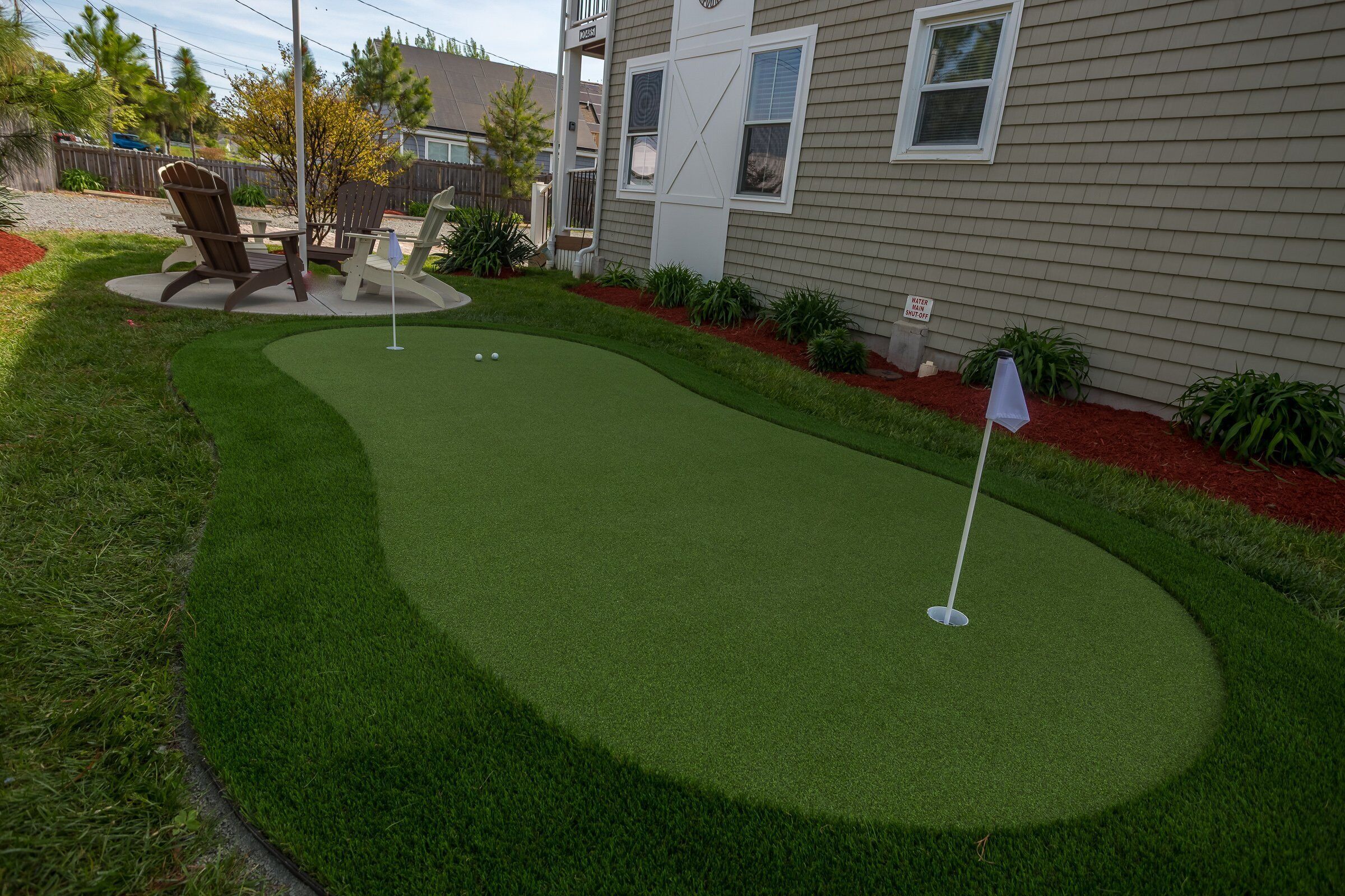 A miniature golf course with artificial turf, a putting green, and a flag.