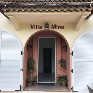 Der Eingang einer Villa, mit der Aufschrift "Villa Mina" über einem Ziegeldach.