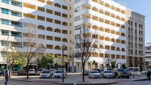 Un hotel de varios pisos con un diseño arquitectónico moderno, que cuenta con balcones y un patio central.