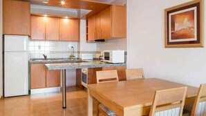 Una cocina compacta con armarios de madera, un microondas y un comedor con mesa y sillas.