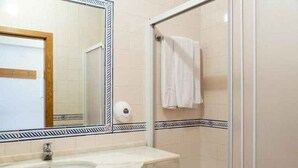 Un baño con lavamanos, espejo y ducha.