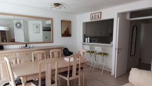 A dining area with a wooden table and chairs, a kitchen with cabinets and a sink, and a living area with a sofa.