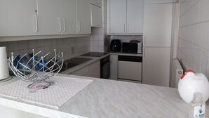 A kitchen with white cabinets, a microwave, a coffee maker, and a dish rack.