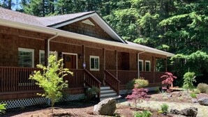 A wooden cabin with a porch, surrounded by a landscaped garden with various plants and rocks. - Spectacular Golf Group Vacation Rental at Bandon Dunes Golf Resort (Bandon)