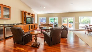 A spacious living room with a fireplace, a dining area, and a kitchen with wooden cabinets and a built-in oven. - Spectacular Golf Group Vacation Rental at Bandon Dunes Golf Resort (Bandon)