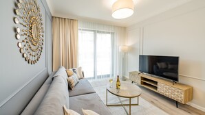 A modern living room with a sofa, TV, and decorative wall piece. - Rezydencja Niechorze (Rewal)