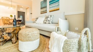 A modern living room with a sofa, round coffee table, and woven poufs. - Rezydencja Niechorze (Rewal)