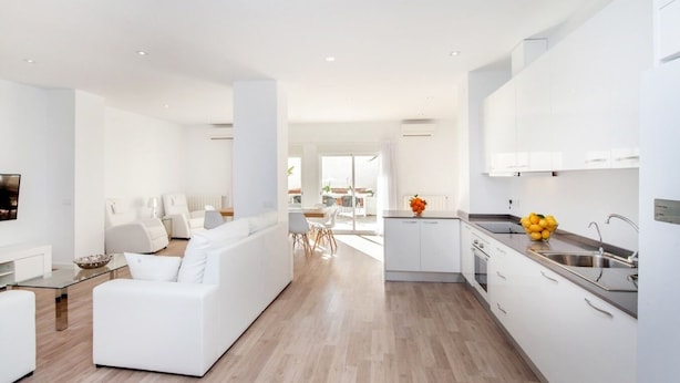 Una cocina moderna con armarios blancos y un lavamanos de acero inoxidable.
