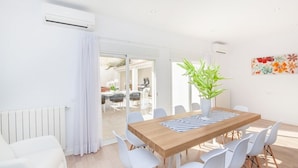 Un comedor luminoso y moderno con una mesa de madera, sillas blancas y una planta en maceta.