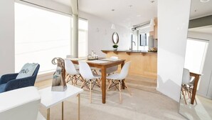 A modern kitchen with a wooden countertop, white cabinets, and a hanging light fixture. - TWO Modern Penthouses on Mass by CozySuites (Indianapolis)