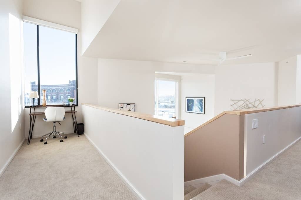 A modern apartment with a large window, a desk, and a view of a cityscape.