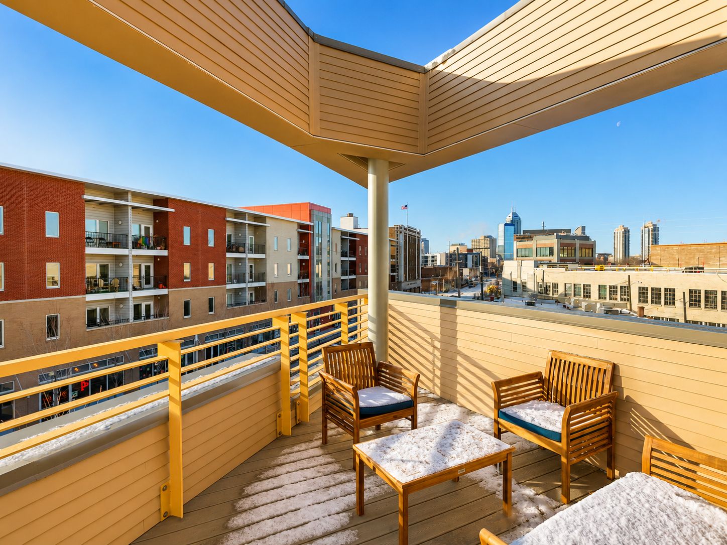 A balcony with wooden furniture and a city view.