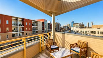 A balcony with wooden furniture and a city view.