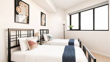 A hotel room with two beds, a large window, and artwork on the walls.