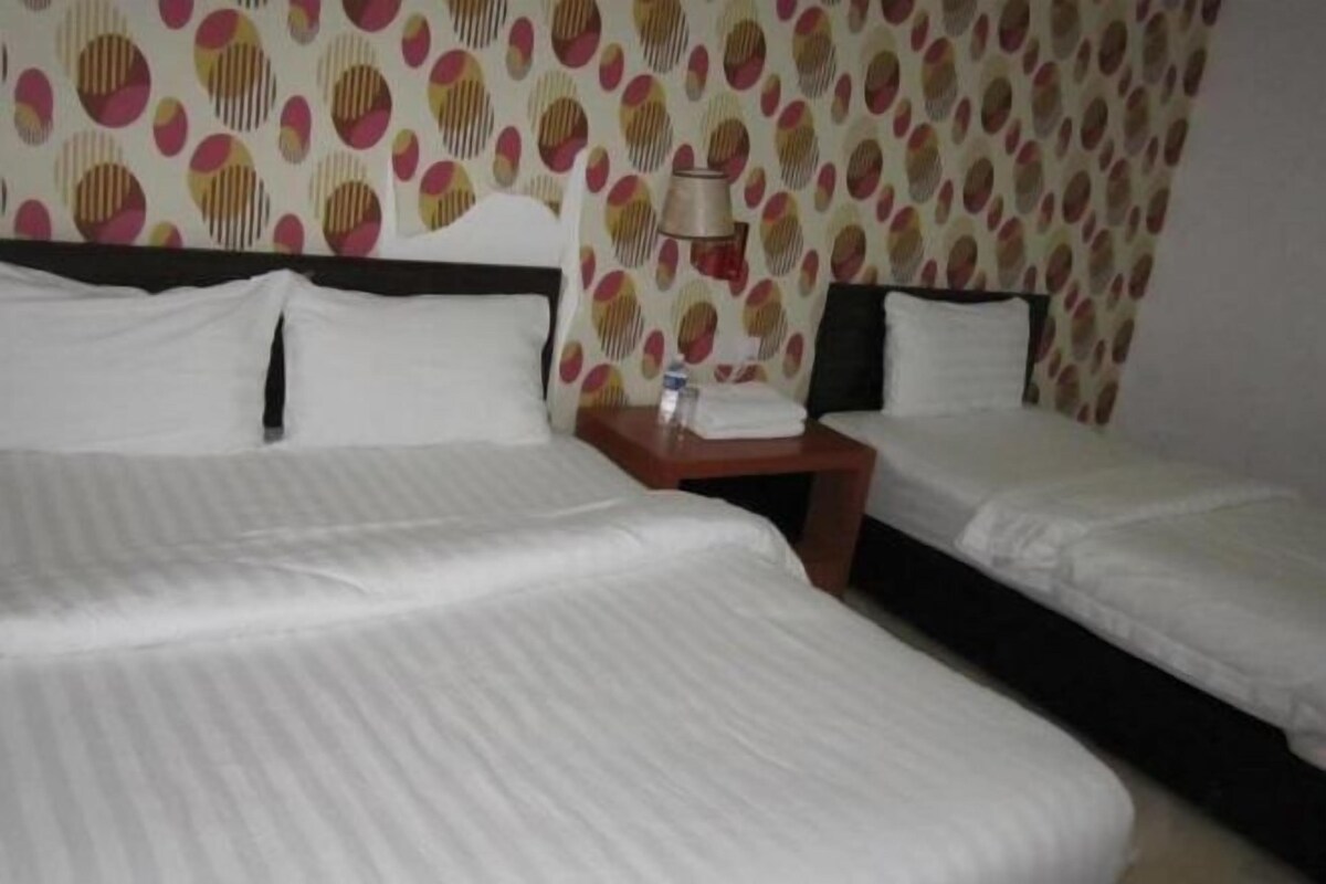 A hotel room with two beds, a nightstand, and a patterned wallpaper.