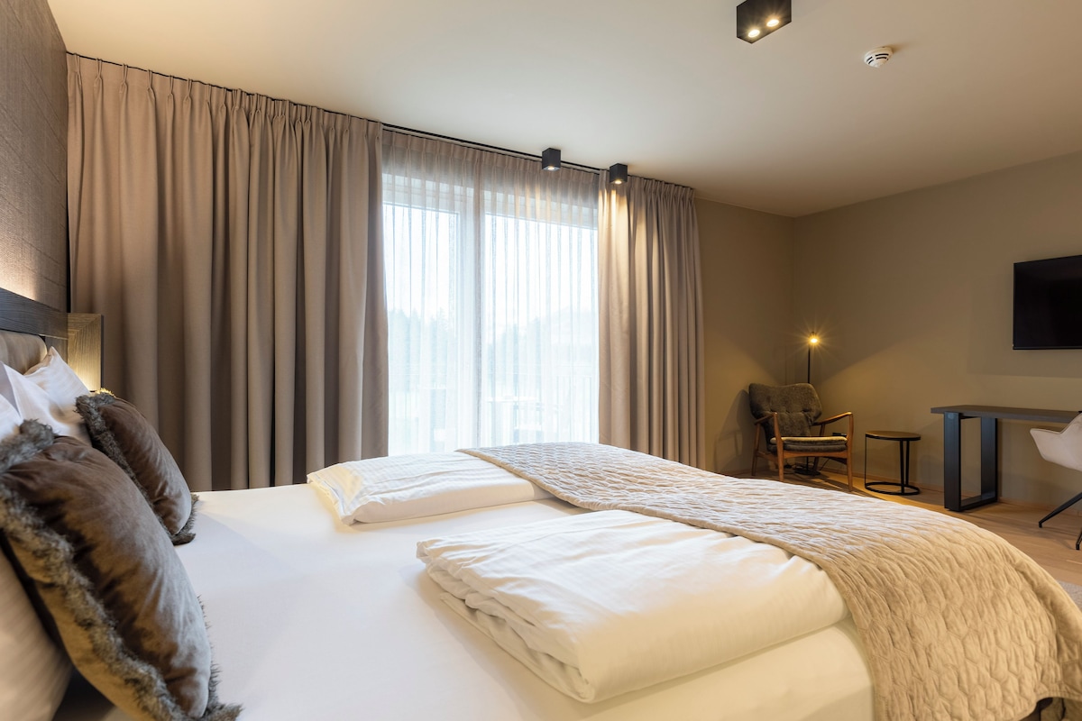 Une chambre d’hôtel avec un grand lit, une chaise, un bureau et un téléviseur fixé au mur.