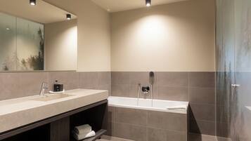 Ein modernes Badezimmer mit einem großen Spiegel, zwei Waschbecken, einer Badewanne und einer Dusche.