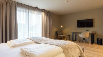 A modern hotel room with a large bed, a desk, and a TV.